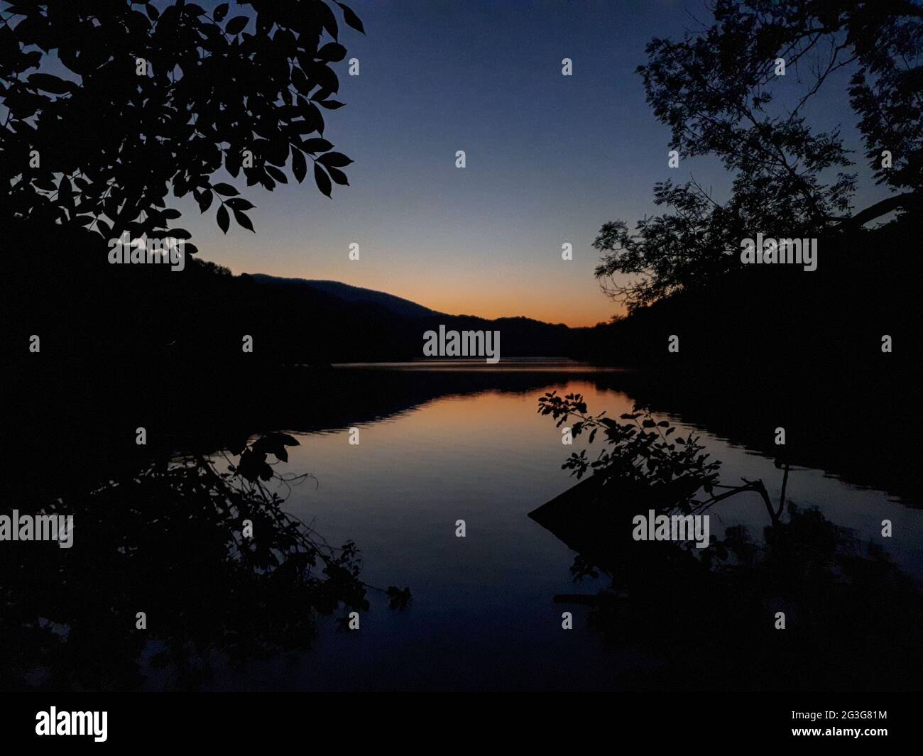 crepuscolo sul lago con alberi e silhouette di montagna contro il cielo serale in Croazia Foto Stock