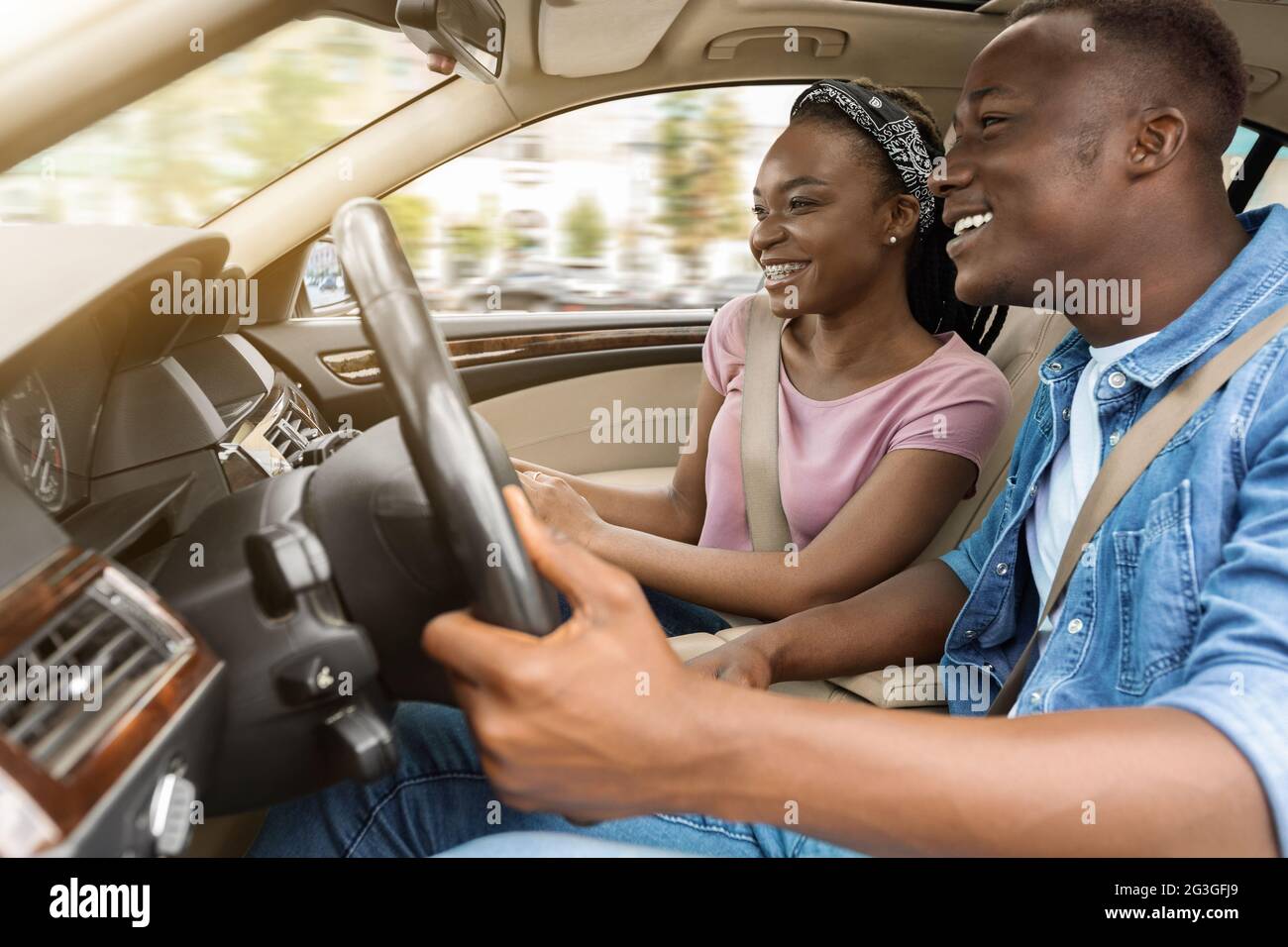 Marito nero e moglie amorevoli che viaggiano insieme in auto Foto Stock