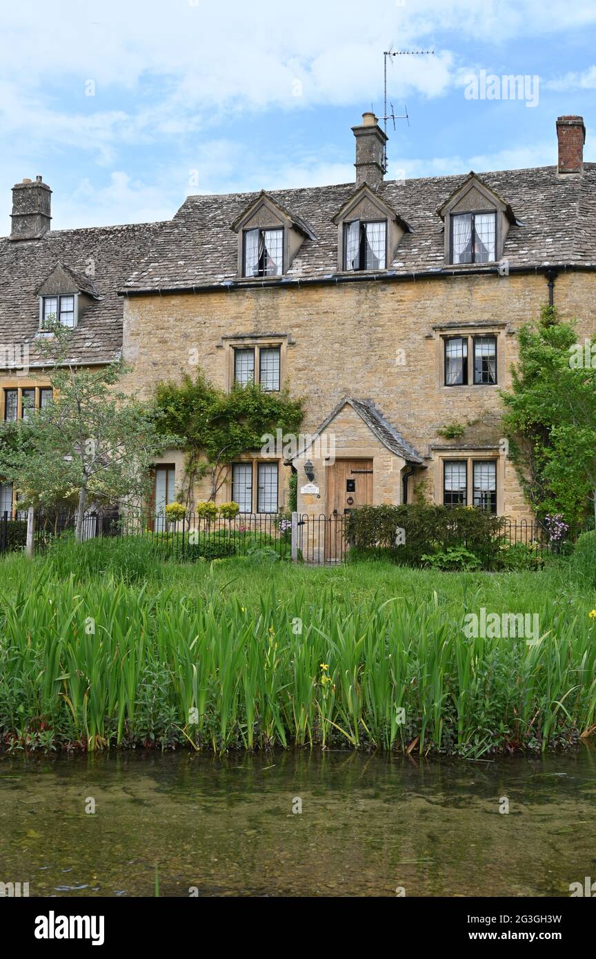 Una fila di case si trova vicino al River Eye che scorre attraverso il pittoresco villaggio di Lower Slaughter, una popolare destinazione turistica in questa parte o Foto Stock