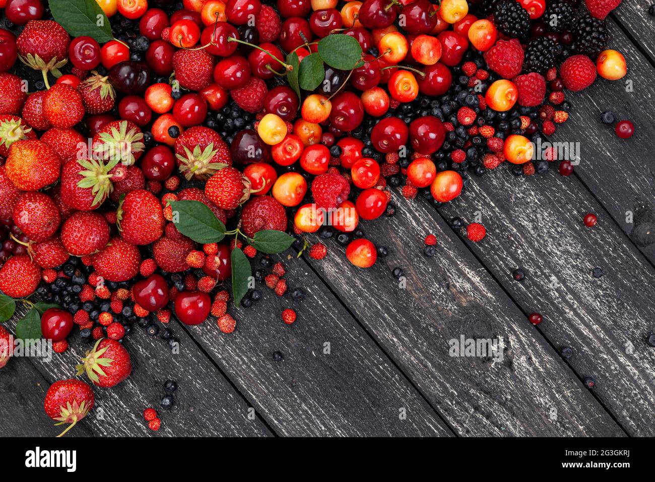 Frutti di bosco freschi su sfondo di legno nero, vista dall'alto Foto Stock