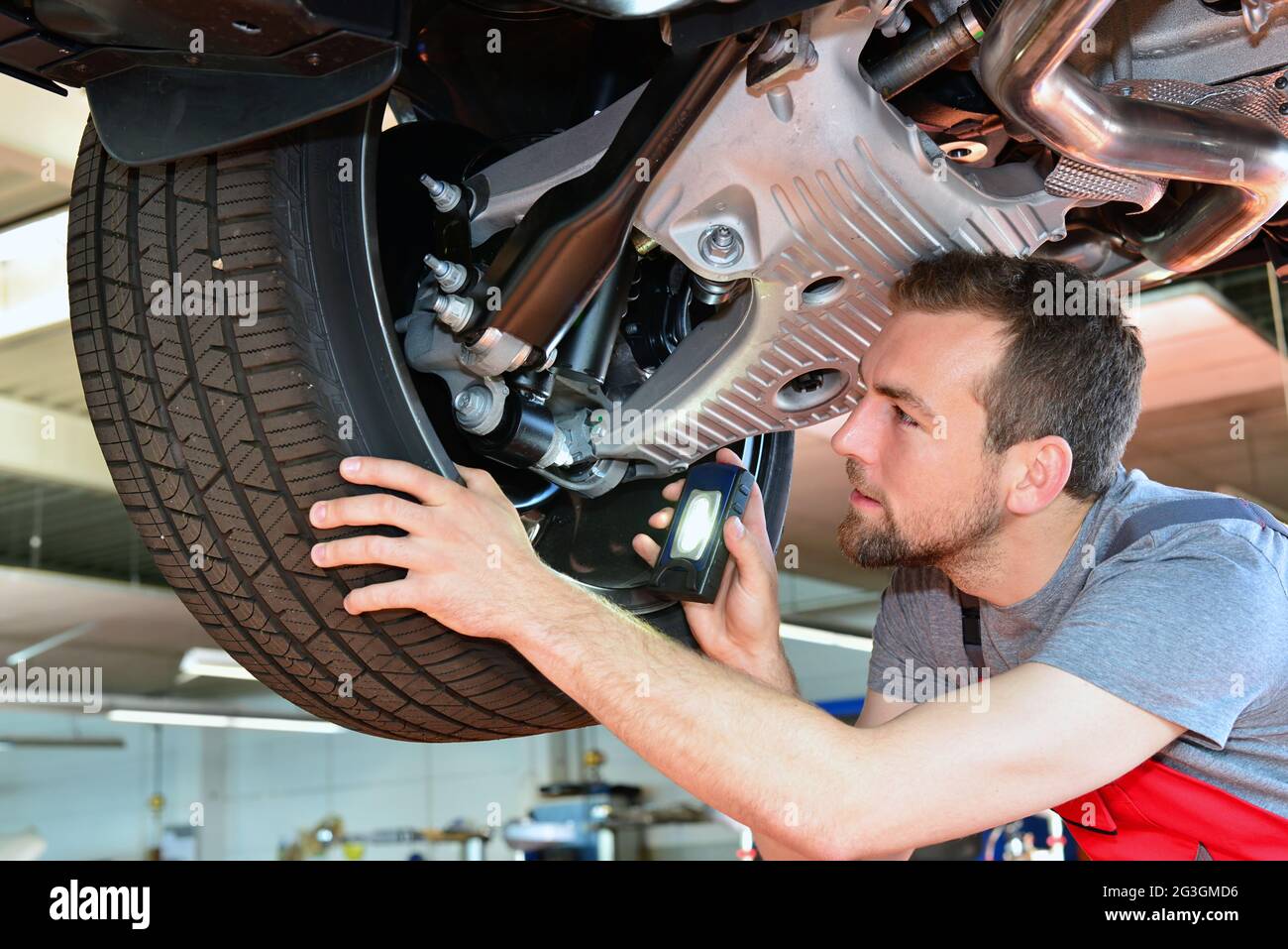 Il meccanico automatico ripara il veicolo in officina - verifica della sicurezza dei freni Foto Stock