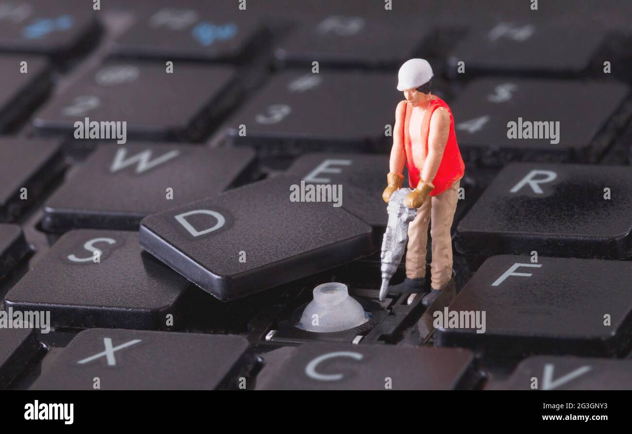Lavoratore in miniatura con trapano che lavora sulla tastiera Foto Stock