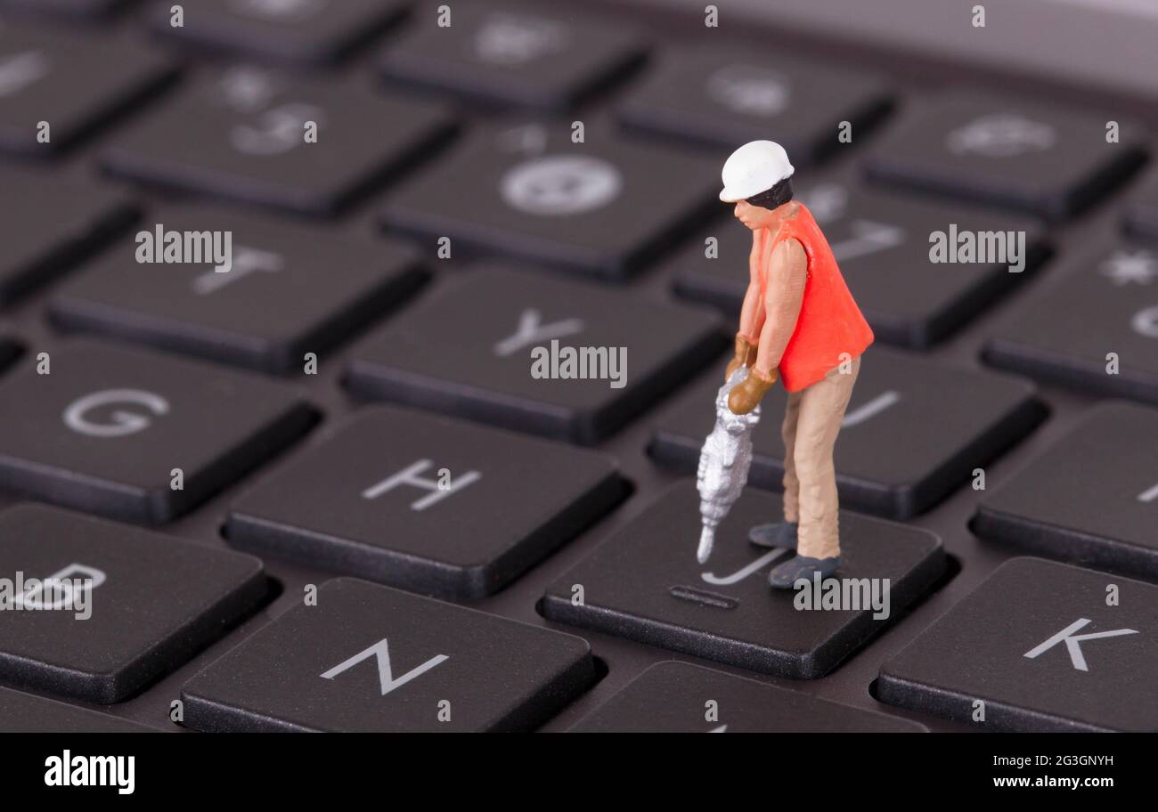 Lavoratore in miniatura con trapano che lavora sulla tastiera Foto Stock