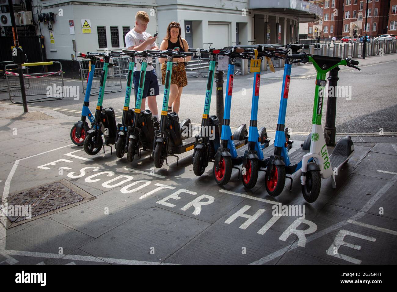 Una coppia che noleggia e-scooter a Hammersmith - uno dei comuni dove da lunedì 7 giugno 2021 scooter elettrici è diventato disponibile per l'affitto a Londra. Foto Stock