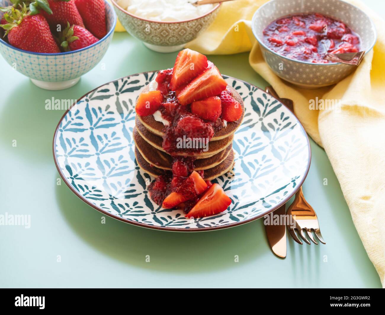 Frittelle di grano saraceno senza glutine di banana, servite con yogurt senza latte e marmellata di fragole di chia Foto Stock