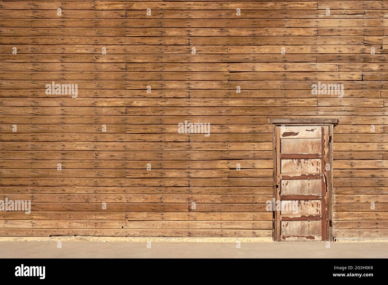Vecchio edificio in legno con una parete esterna con una porta e pavimento in marrone Foto Stock