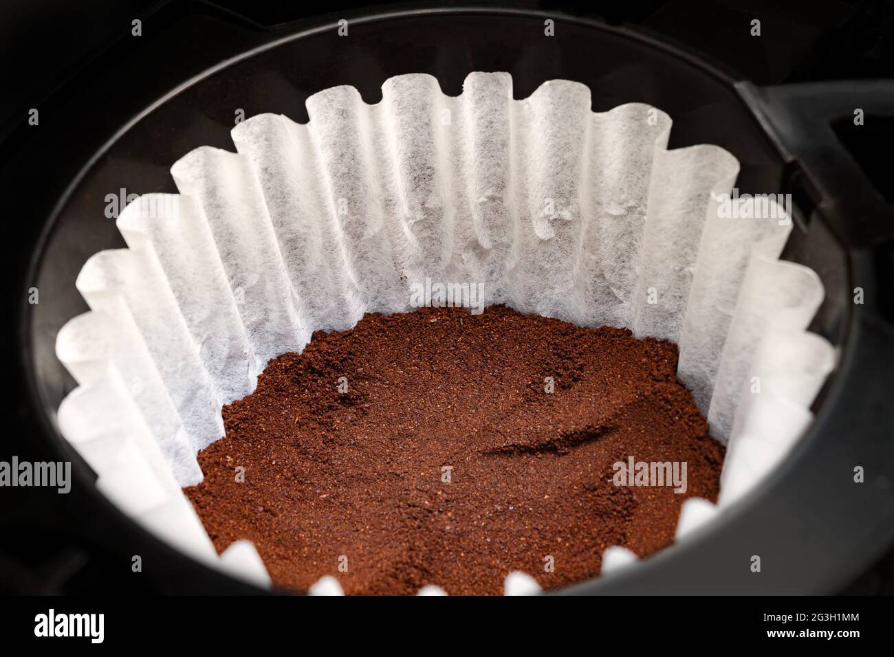 Caffè finemente macinato in un filtro di carta bianca in una macchina antigoccia Foto Stock