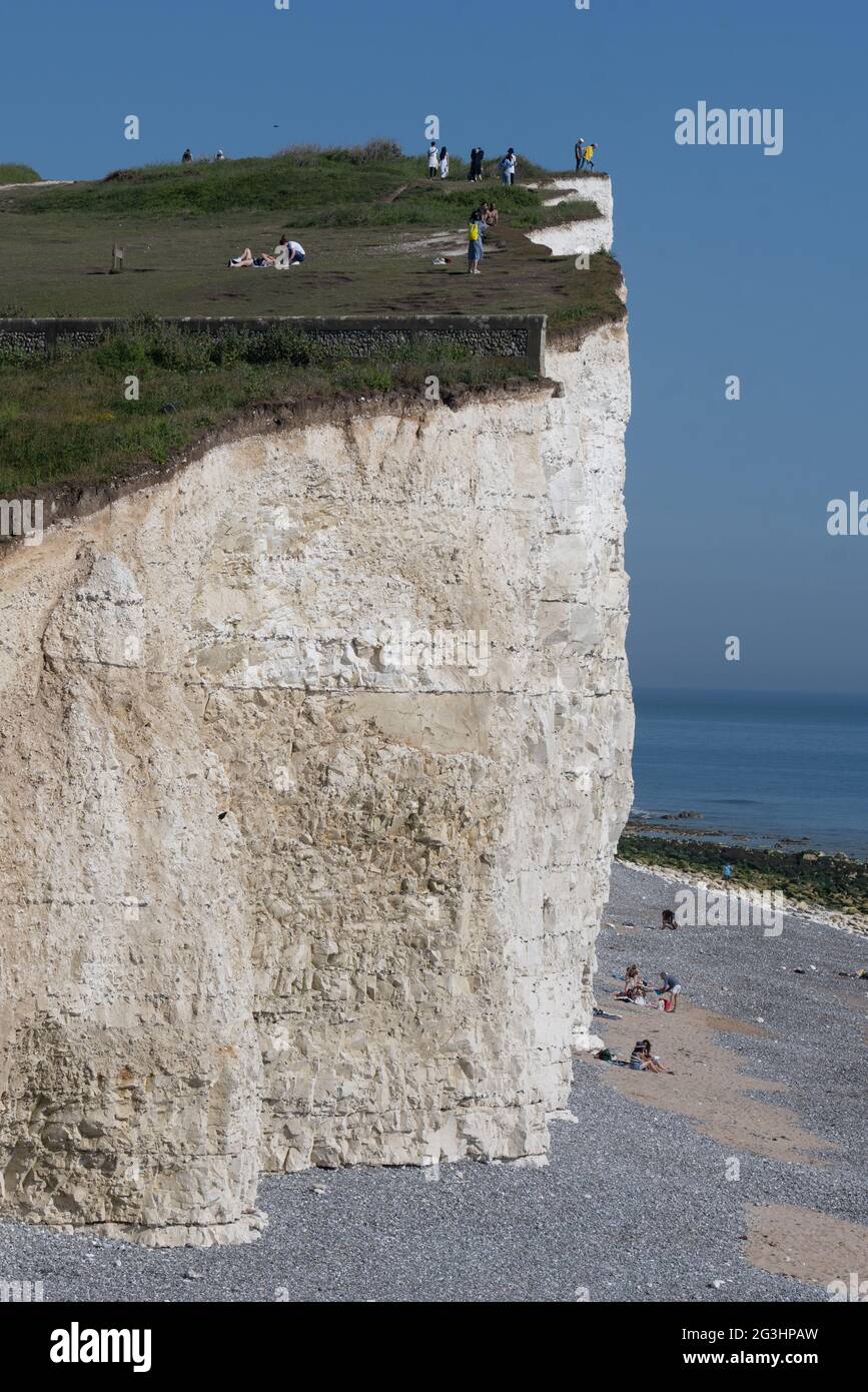 I bagnanti scelsero probabilmente il posto più pericoloso per prendere il sole mentre si inzuppavano il sole estivo proprio sotto il bordo della scogliera a Beachy Head, East su Foto Stock