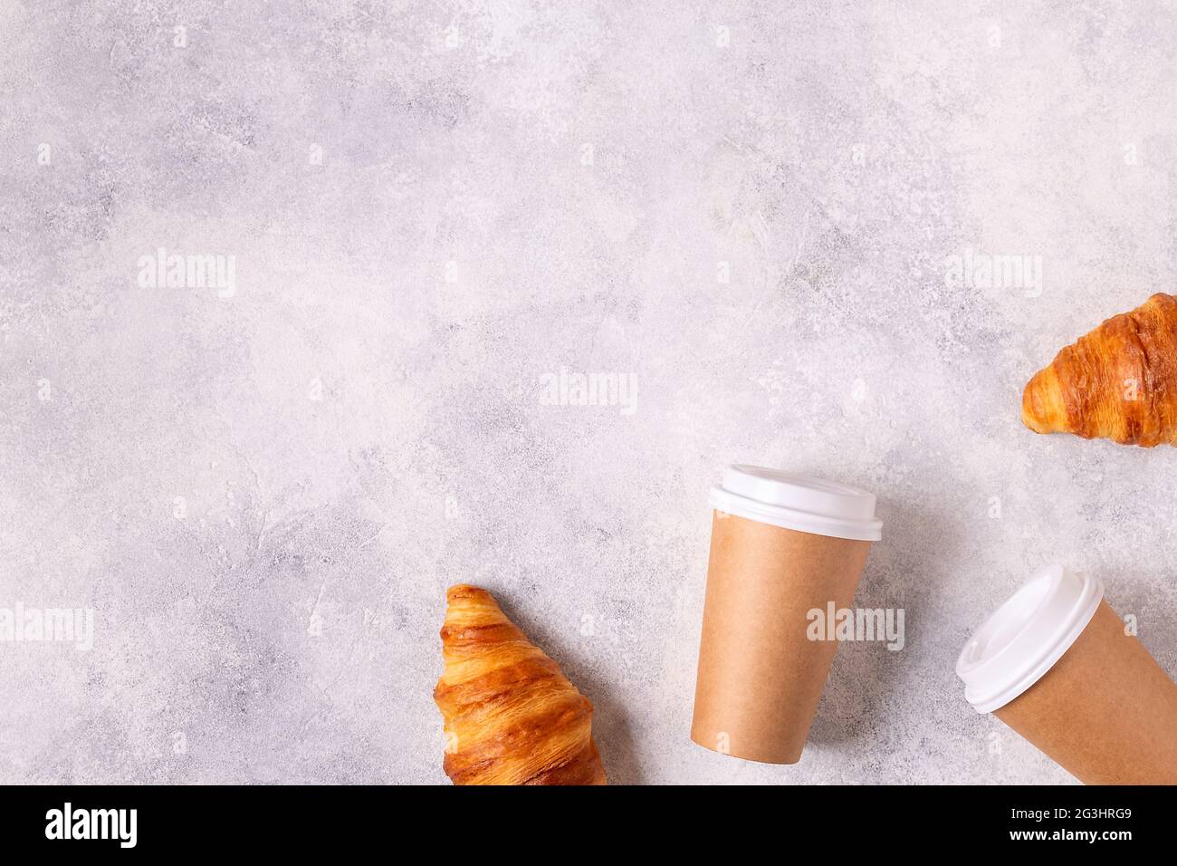 Caffè da gustare in una tazza di carta con croissant, vista dall'alto. Foto Stock