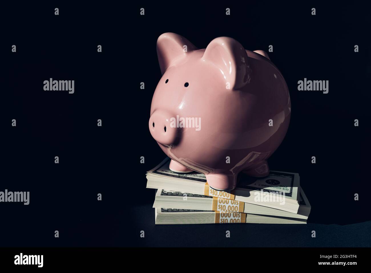 Concetto di gestione patrimoniale. Pile di 100 dollari di risparmio si accumularono sotto il concetto di banca piggy. Budget, investimenti, economia. Foto Stock