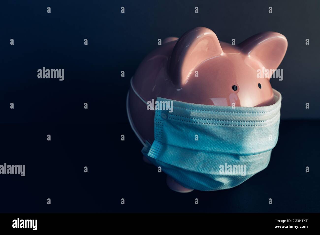 Economia globale durante la pandemia del coronavirus. Banco di piggy con maschera chirurgica per il viso. Crisi finanziaria, concetto bancario. Foto Stock