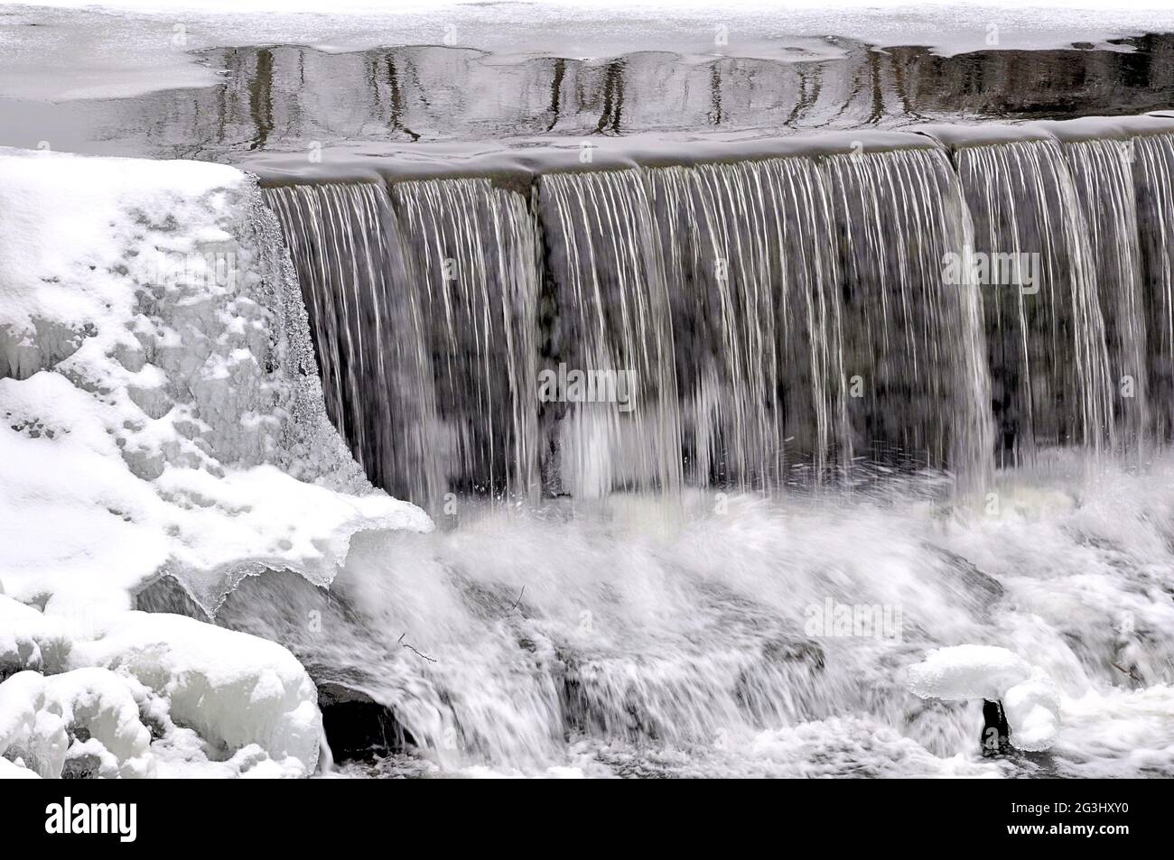 Scena invernale in New England. Formazioni di ghiaccio ricoperte da polvere di neve fresca e cascata che si riversarono sulla scenografica diga del Porto Pond a Townsend, Mass. Foto Stock