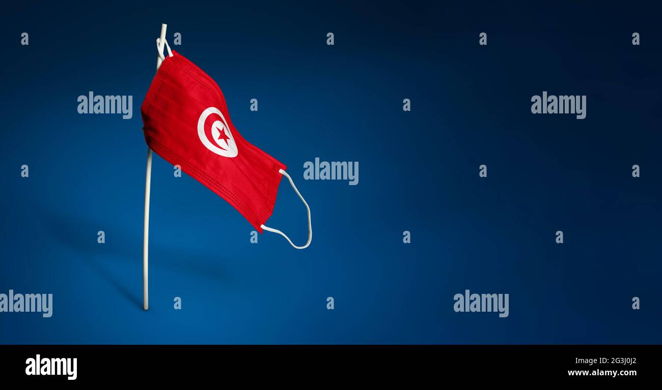 Bandiera sventolante della Tunisia dipinta su maschera medica sul palo. Concetto del banner della lotta contro l'epidemia coronavirus COVID-19. Spazio di copia Foto Stock
