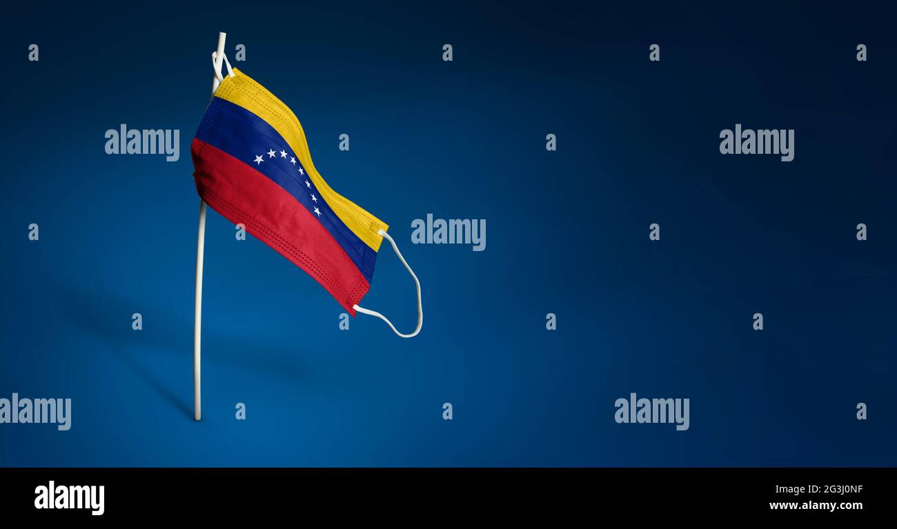 Bandiera ondulata del Venezuela dipinta su maschera medica sul palo. Concetto del banner della lotta contro l'epidemia coronavirus COVID-19. Spazio di copia Foto Stock