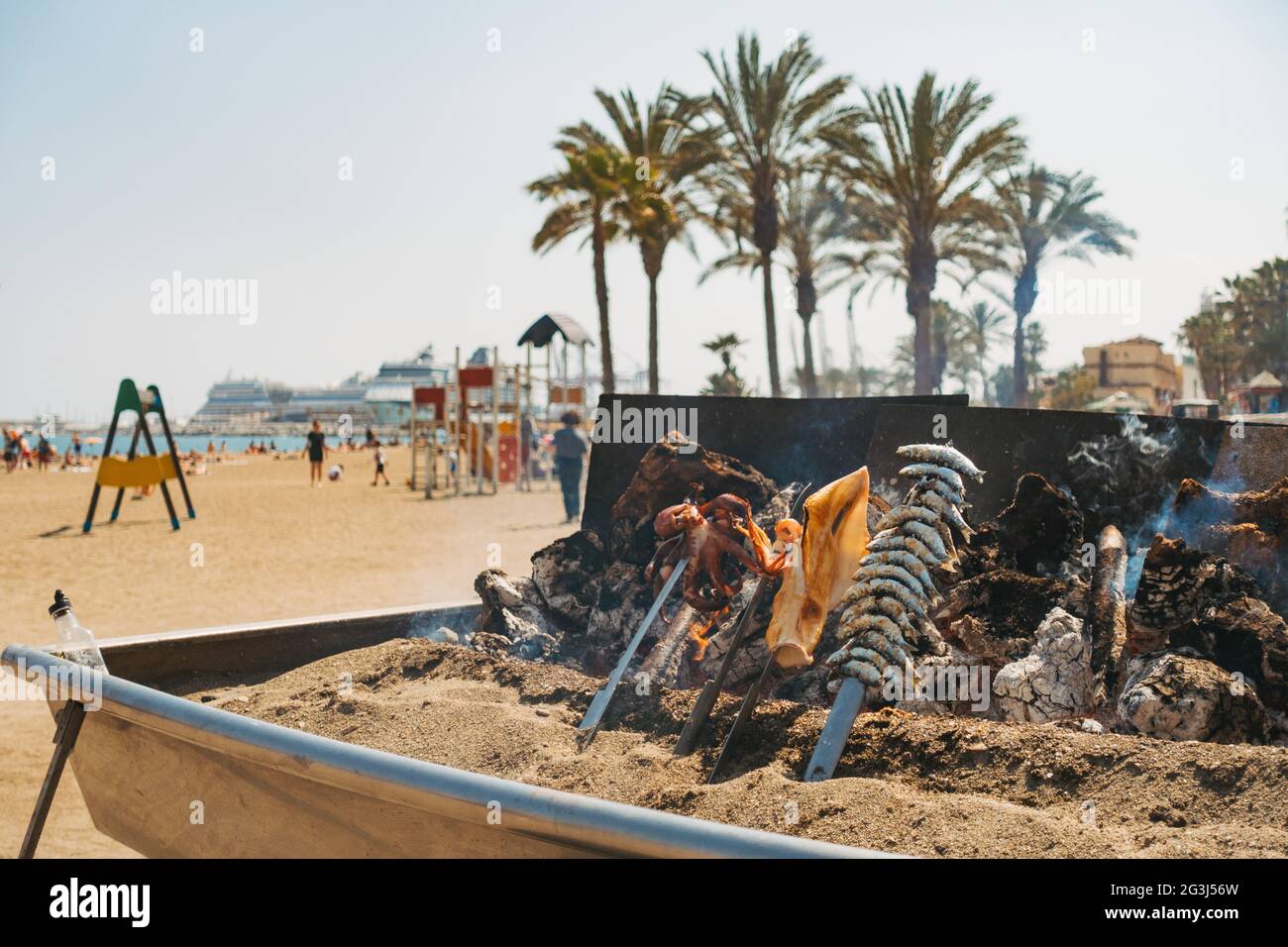 Una varietà di specialità di pesce si cuoce su un barbecue a legna realizzato localmente in un ristorante sulla spiaggia di Malagueta, Málaga, Spagna Foto Stock