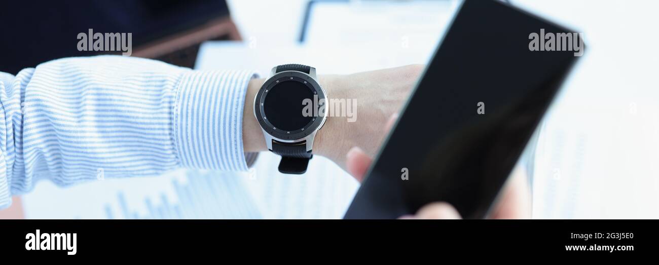 L'uomo tiene lo smartphone in mano e guarda in modo intelligente guarda Foto Stock