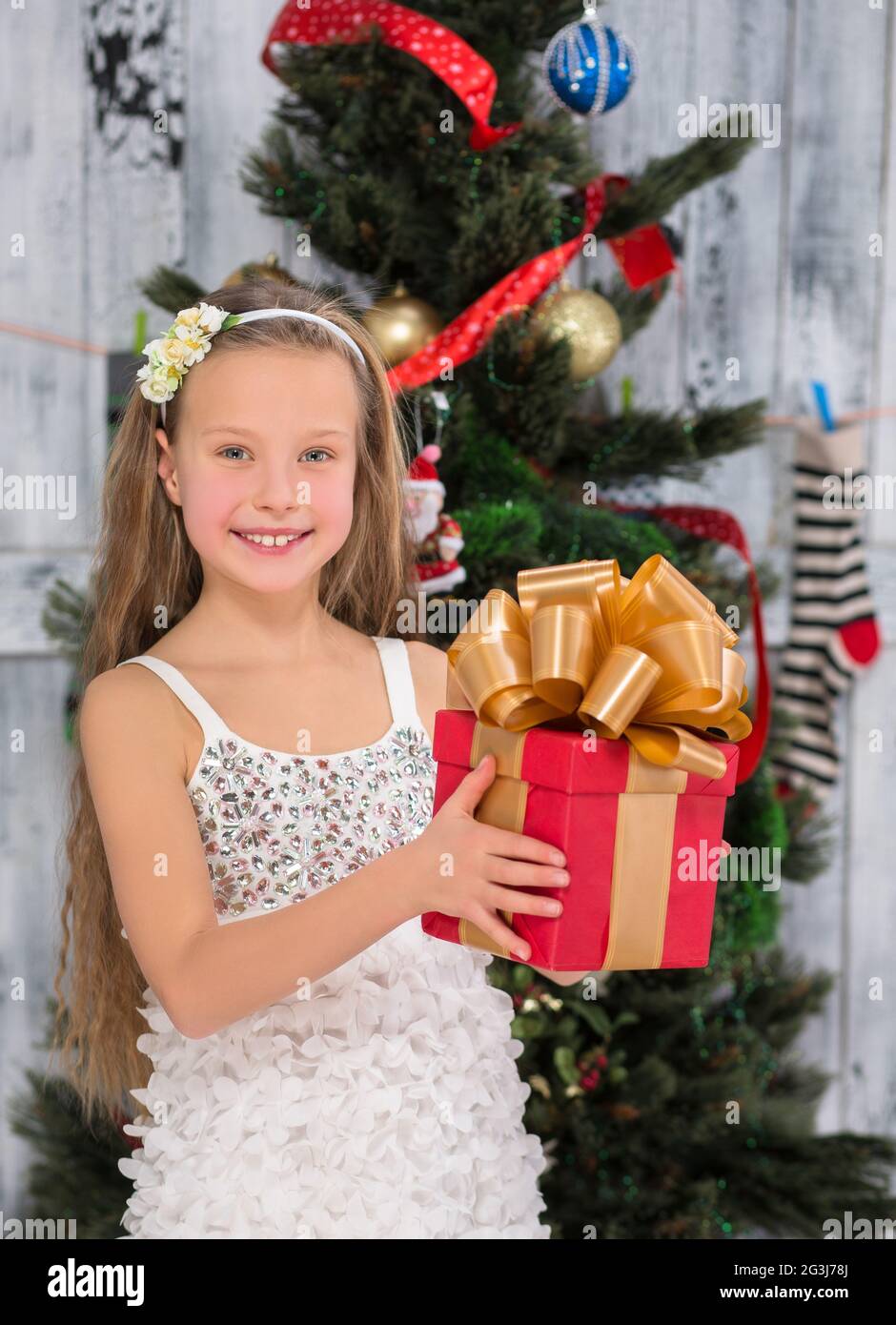 Ragazza adolescente che tiene il regalo di Natale davanti all'albero di Capodanno Foto Stock