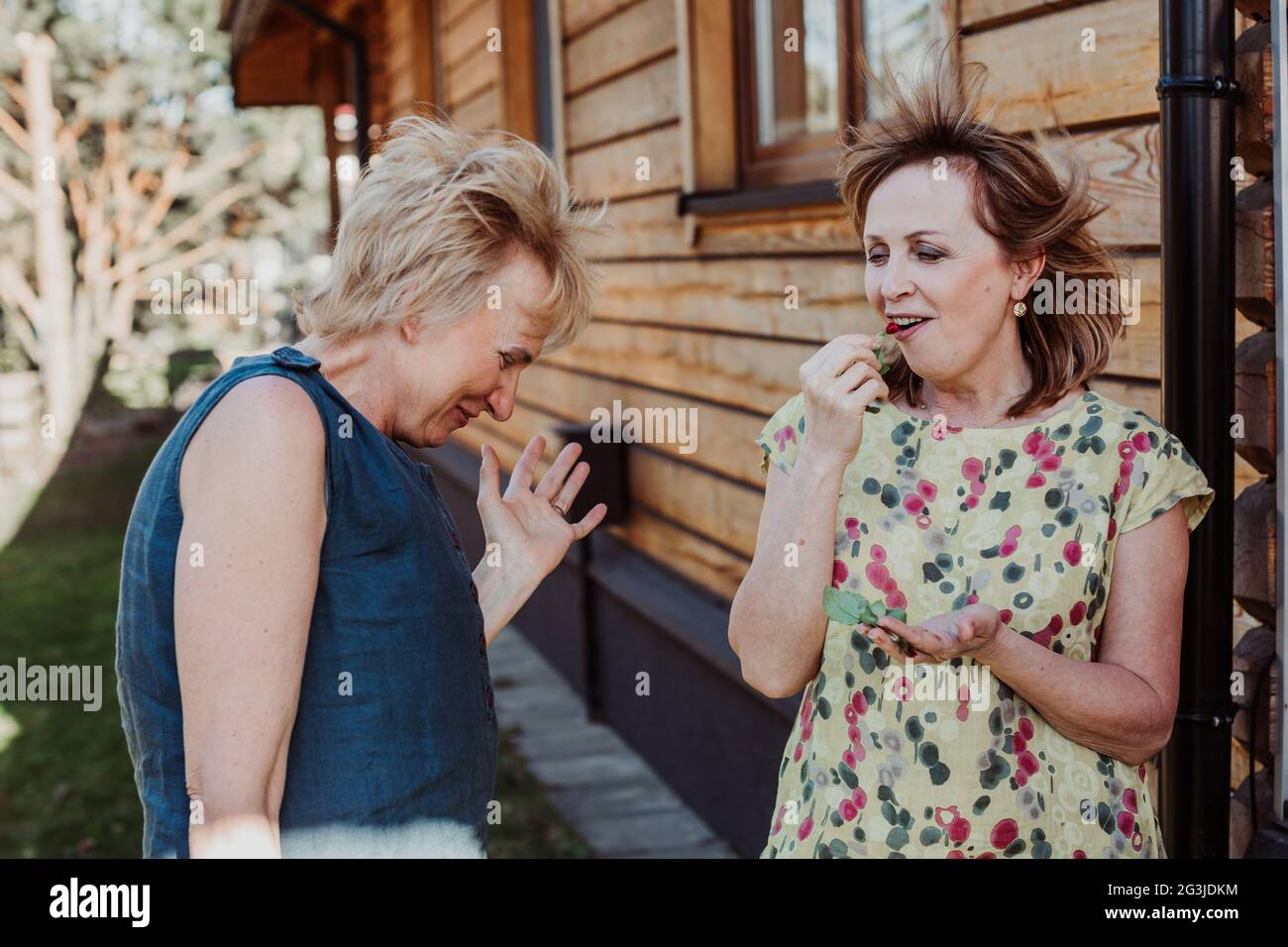 Due donne di 55 anni stanno parlando cute sullo sfondo del muro di legno Foto Stock