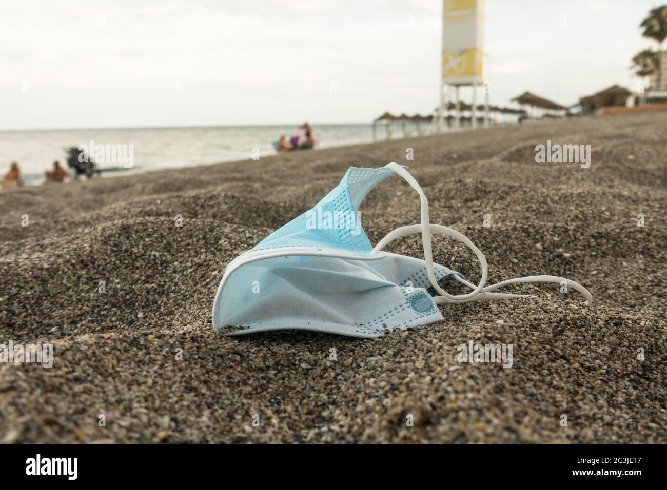 Maschera chirurgica blu lasciata dietro su una spiaggia, Spagna. Foto Stock