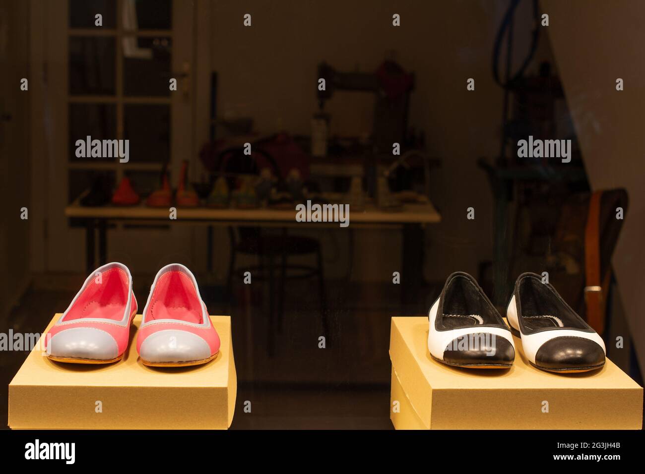 Due paia di scarpe sono stesi sui piedistallo da esposizione in una vetrina  di un laboratorio calzolaio di notte Foto stock - Alamy
