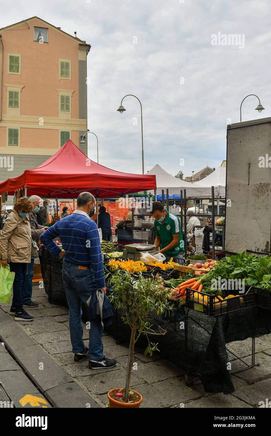 Una coppia anziana e un negozio di articoli per l'uomo in una bancarella di verdure nel mercato di strada vicino al Porto Vecchio di Genova, Liguria, Italia Foto Stock