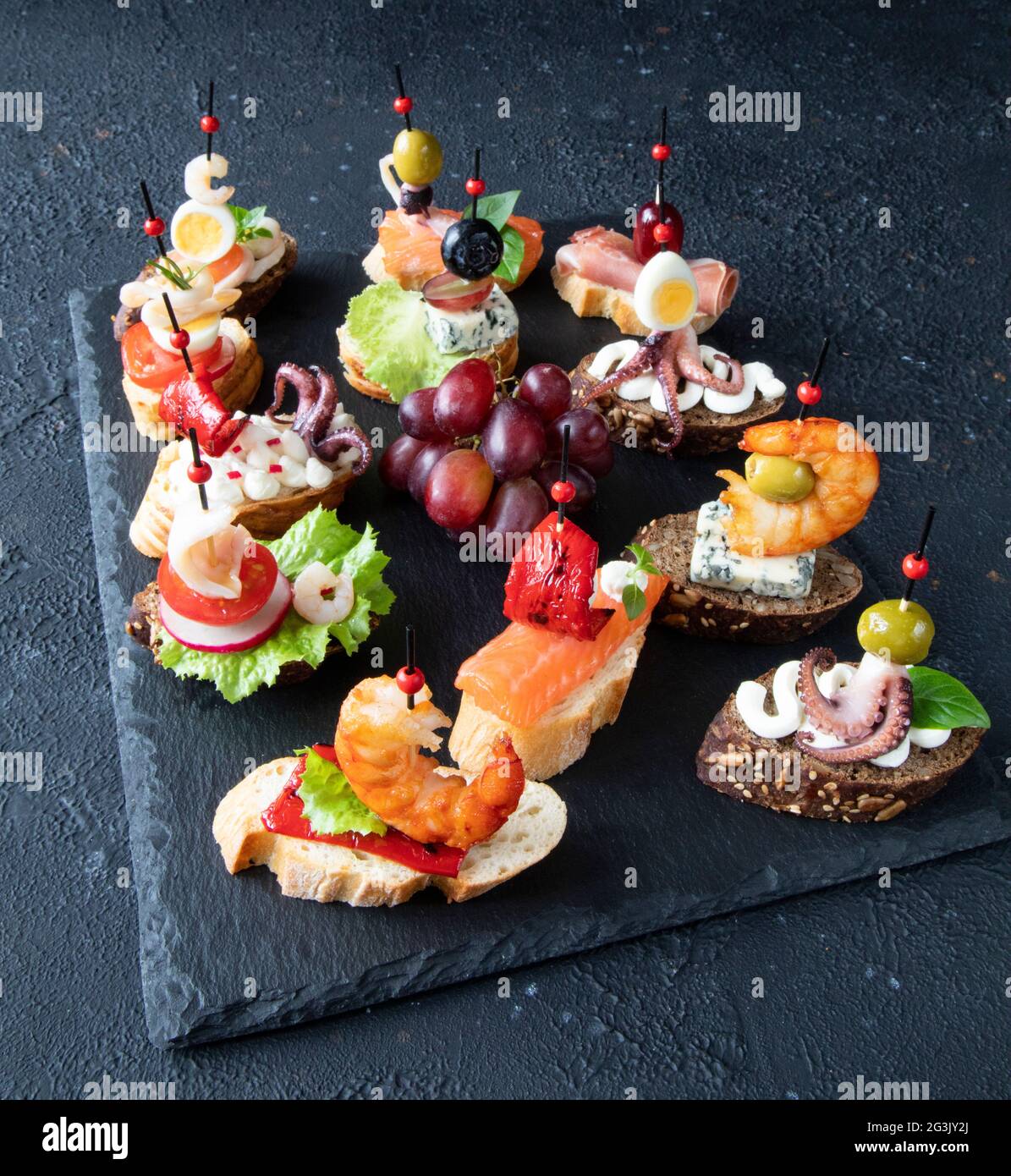 Un set di tradizionali panini con tapas spagnole a base di pesce, gamberi,  calamari, polpi, salmone, uva, gorgonzola, crema di formaggio e baguette  Foto stock - Alamy