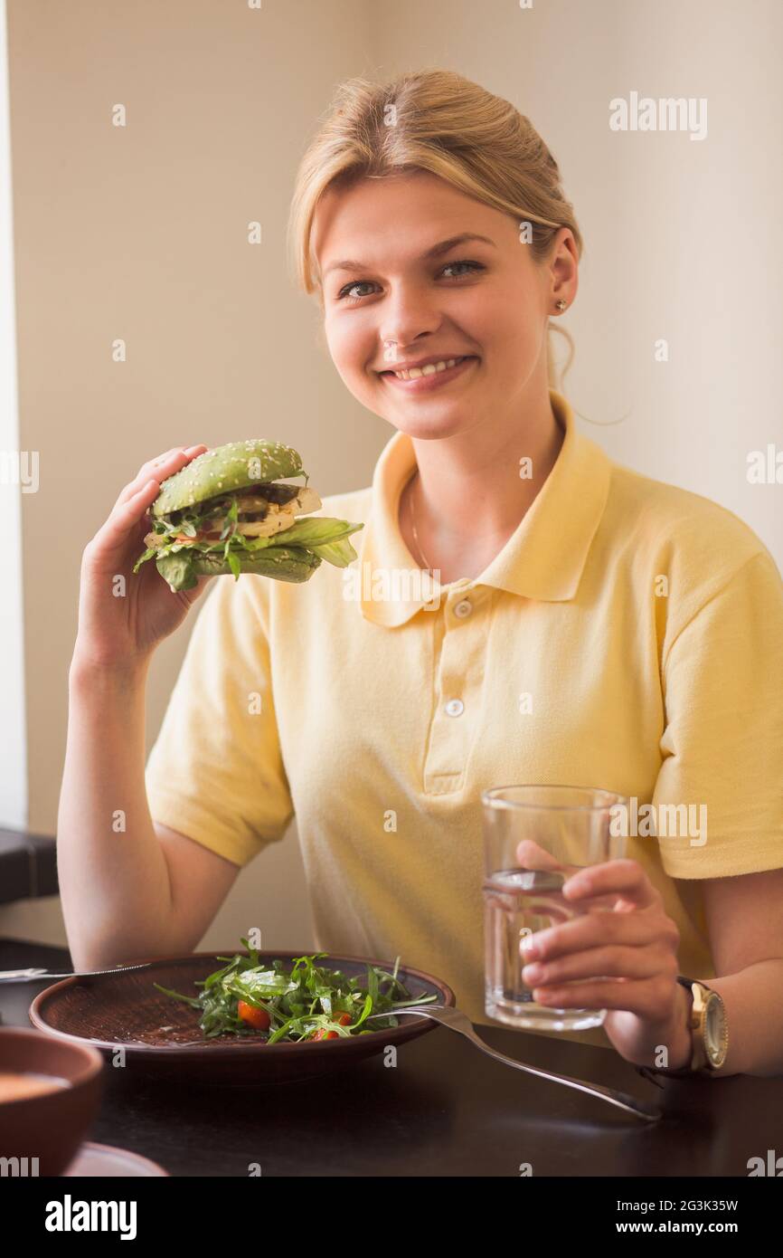 Donna di mangiare vegan burger in ristorante Foto Stock