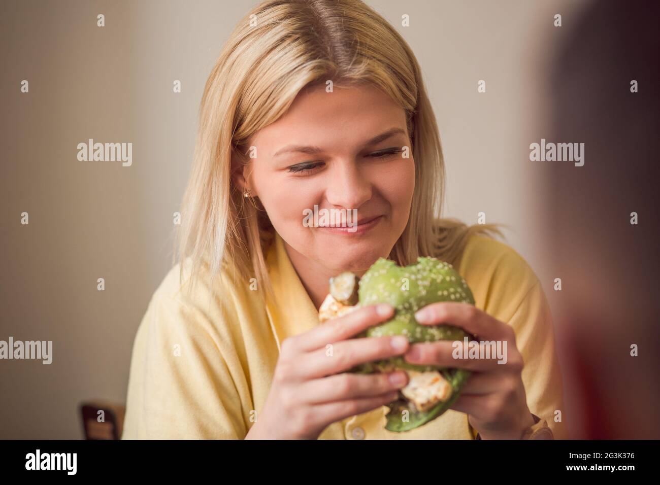 Donna di mangiare vegan burger in ristorante Foto Stock