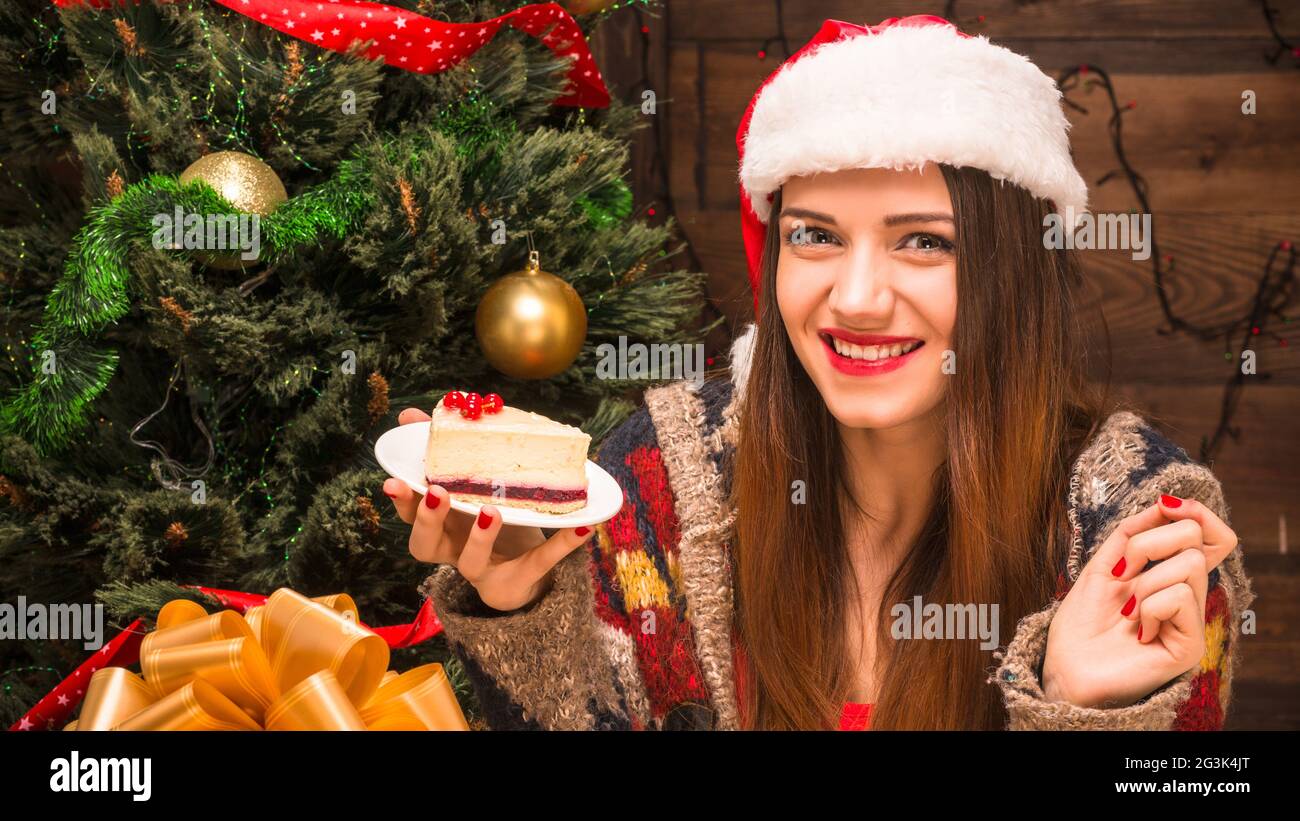 Bella ragazza seduta vicino al Nuovo Anno Albero e mangiare una torta deliziosa Foto Stock