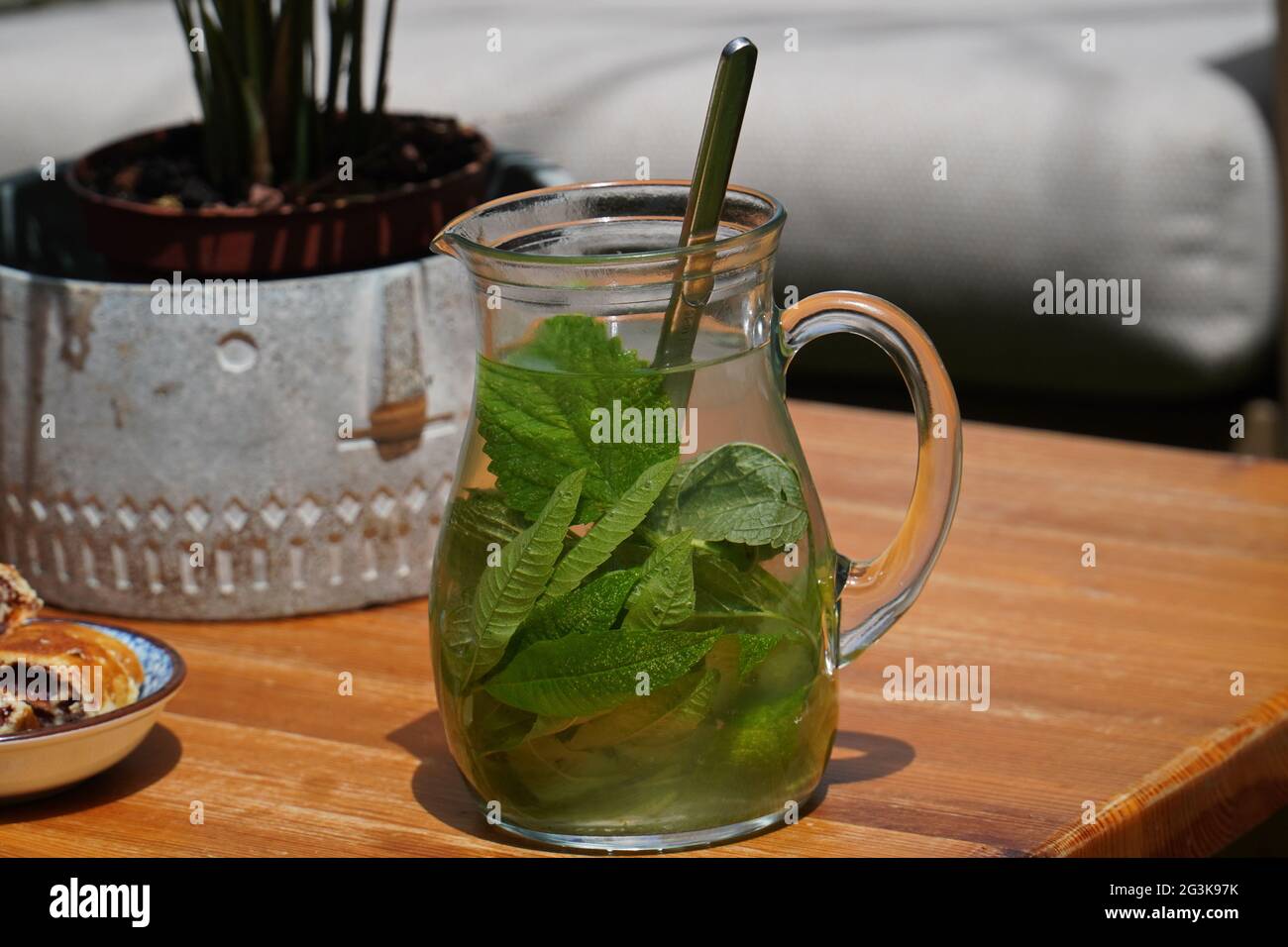 Fuoco selettivo di una caraffa di vetro di tè verde con foglie di menta su un tavolo di legno Foto Stock