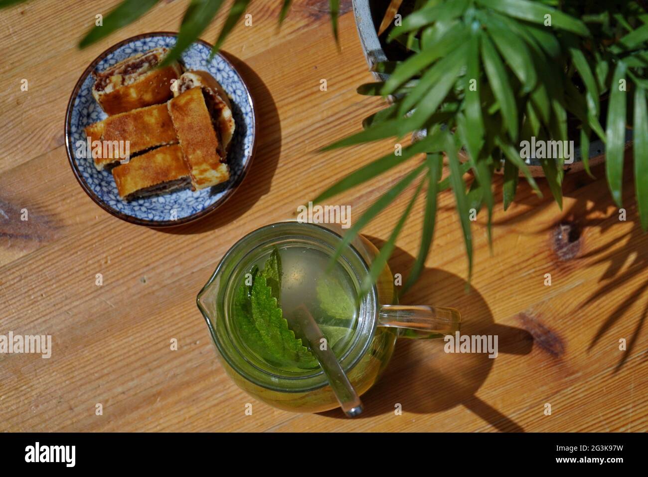 Vista dall'alto di rotoli di noci, piante e una caraffa di vetro di tè verde con foglie di menta su un tavolo di legno Foto Stock