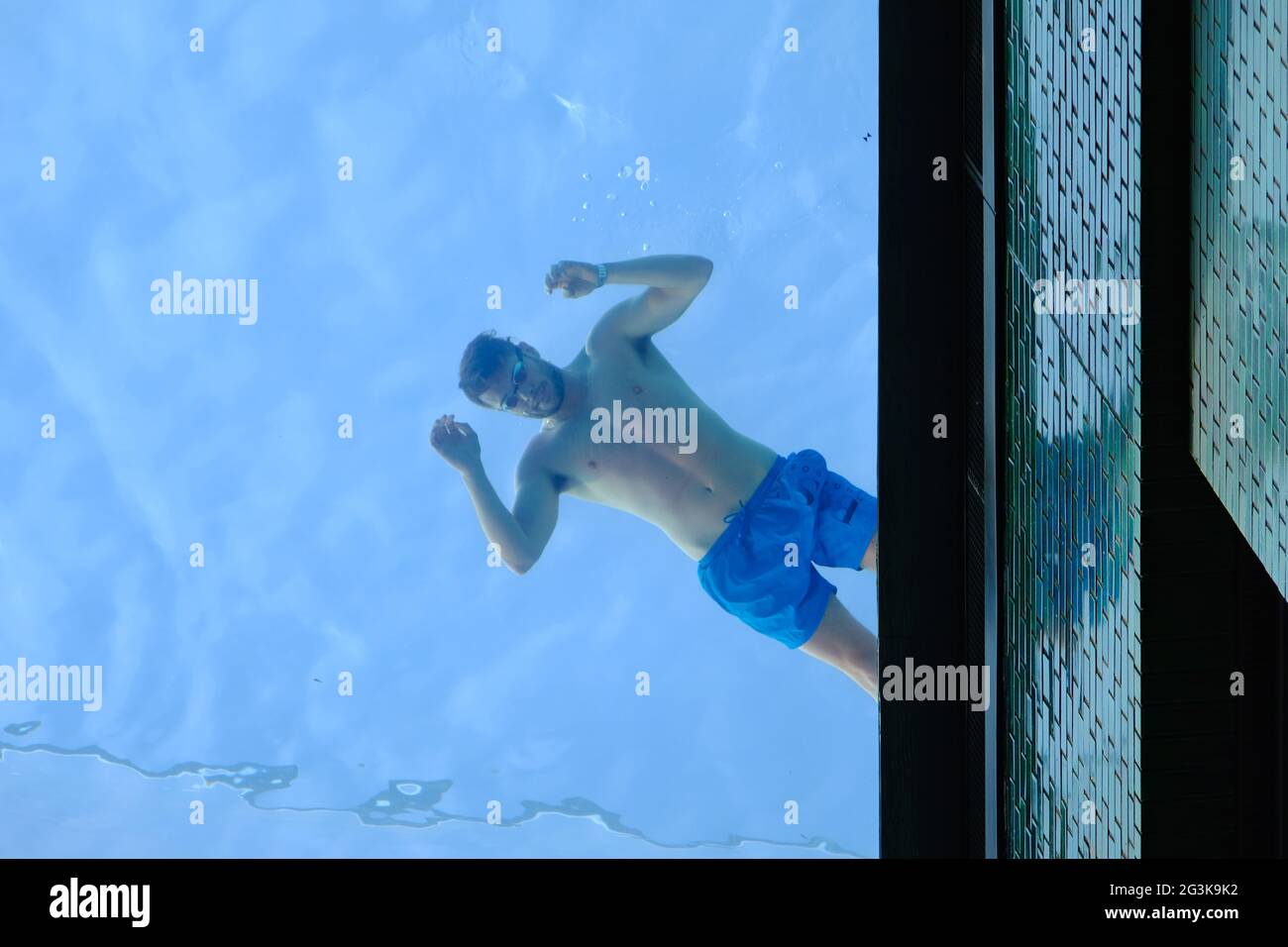 Londra, Regno Unito. Un nuotatore guarda verso il basso attraverso il fondo della piscina trasparente di recente apertura presso Embassy Gardens. Si dice che sia il primo al mondo. Foto Stock