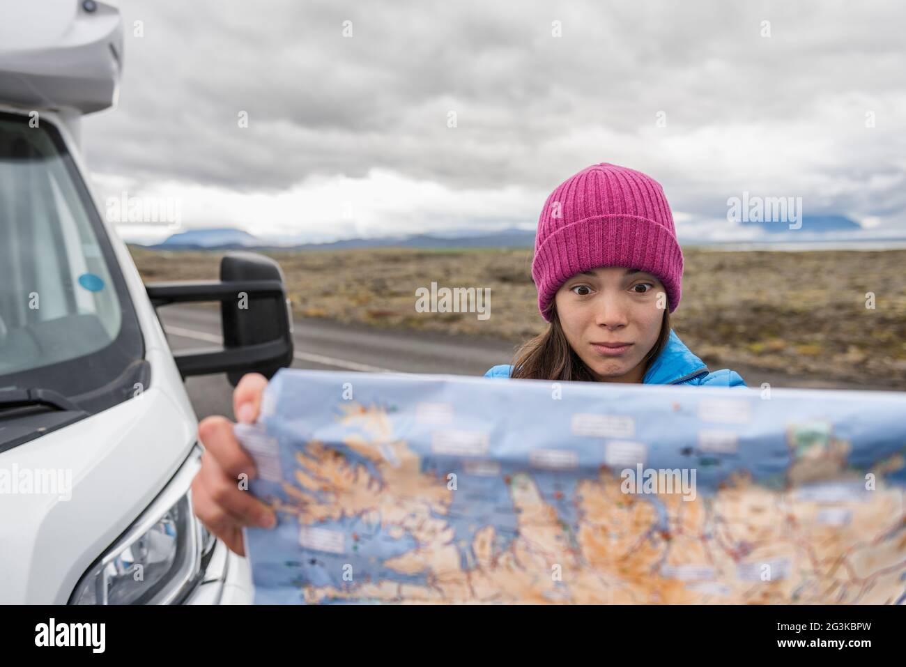 Turisti perduti in Islanda viaggio su strada alla ricerca di indicazioni sulla mappa di viaggio guidare camper casa in Europa avventura vacanza. Faccia divertente asiatica Foto Stock