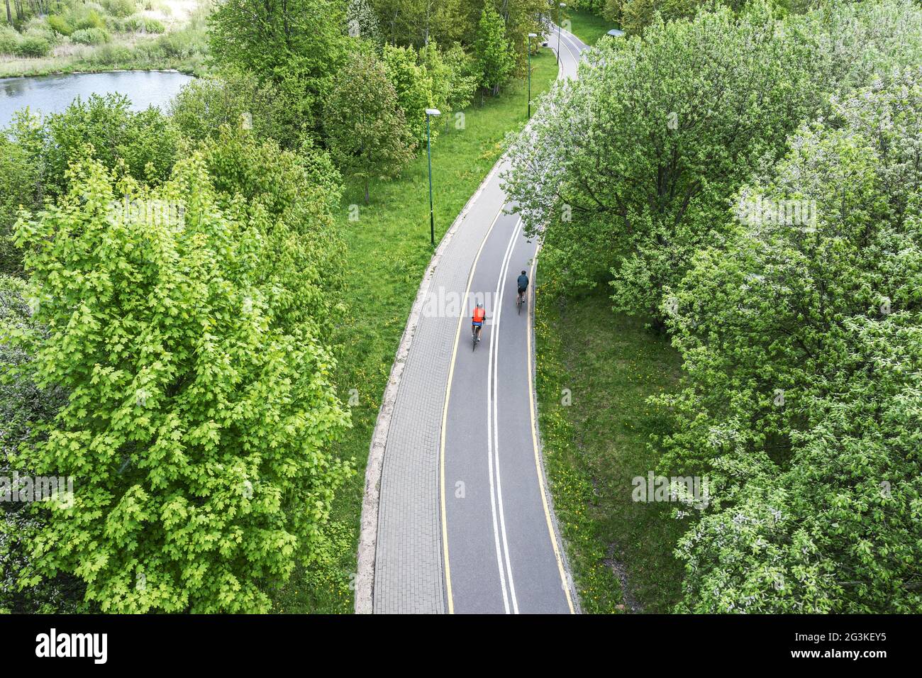 due ciclisti cavalcano le biciclette sulla pista ciclabile nel parco della città in primavera. fotografia aerea con il drone. Foto Stock