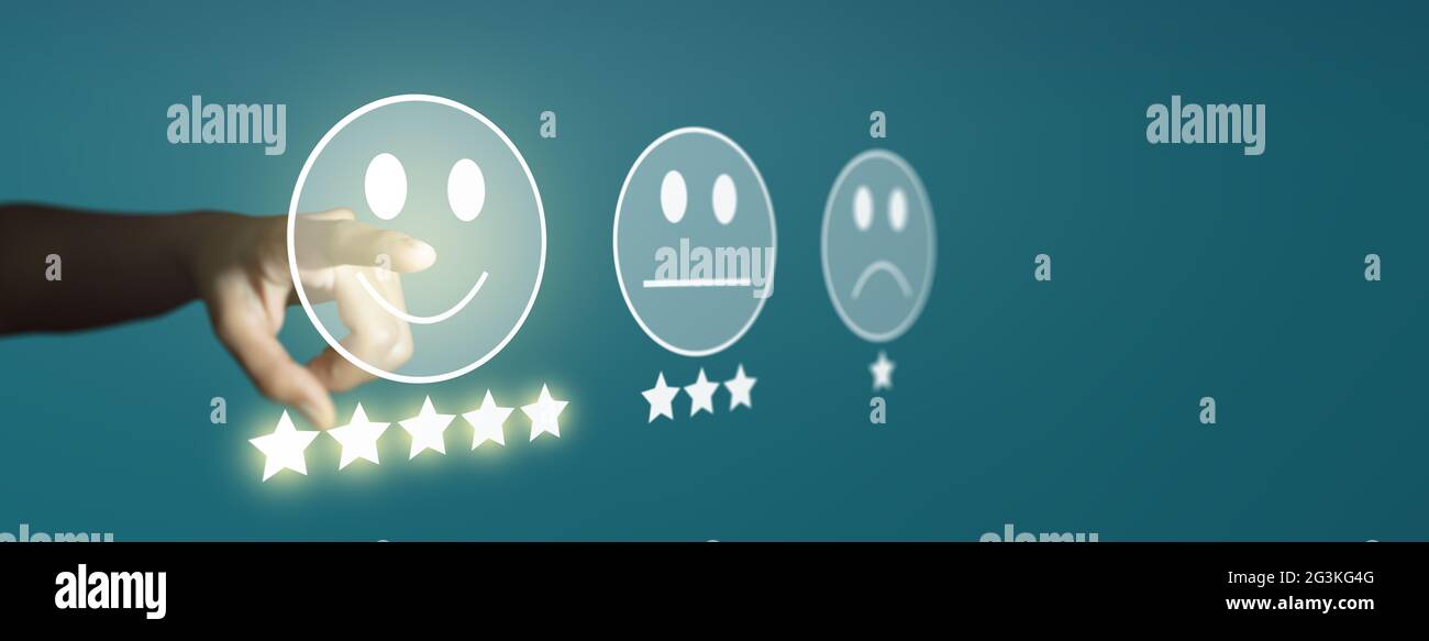 Uomo d'affari che dà la valutazione con emoticon facciali di smiley su touch screen virtuale, sondaggio sulla soddisfazione del cliente e concetto di valutazione del servizio clienti. Foto Stock