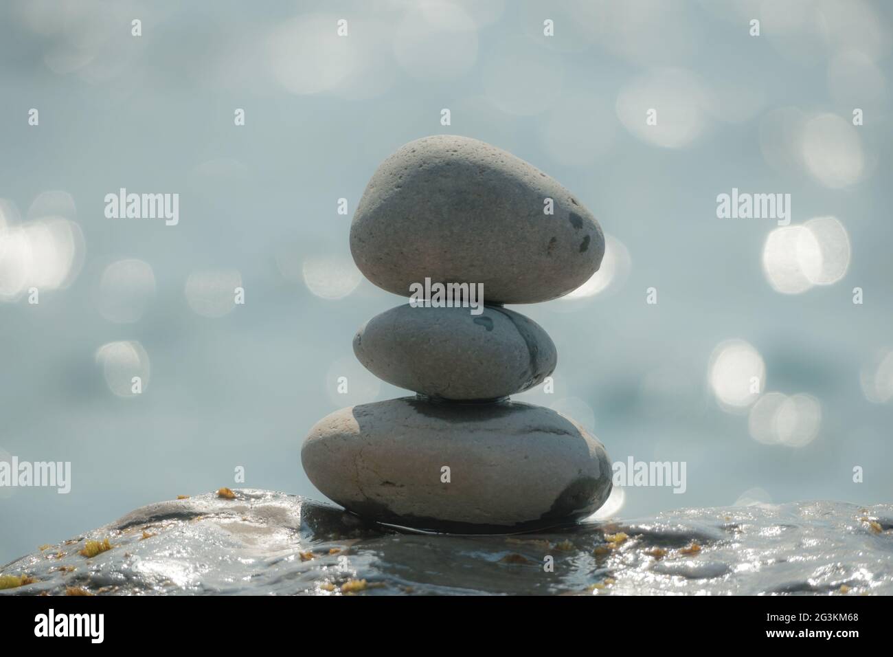 Equilibrata piramide di ciottoli sulla spiaggia in una giornata di sole. Abstract Sea bokeh sullo sfondo. Messa a fuoco selettiva. Pietre Zen sulla spiaggia di mare, meditazione Foto Stock