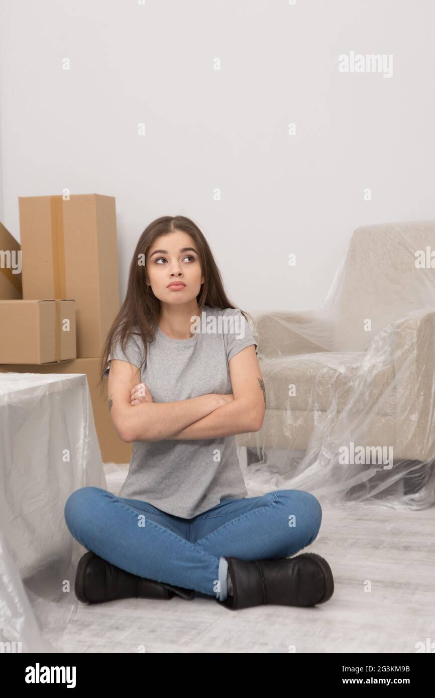 Donna con lunghi capelli scuri relax nel nuovo appartamento dopo il trasferimento. Foto Stock