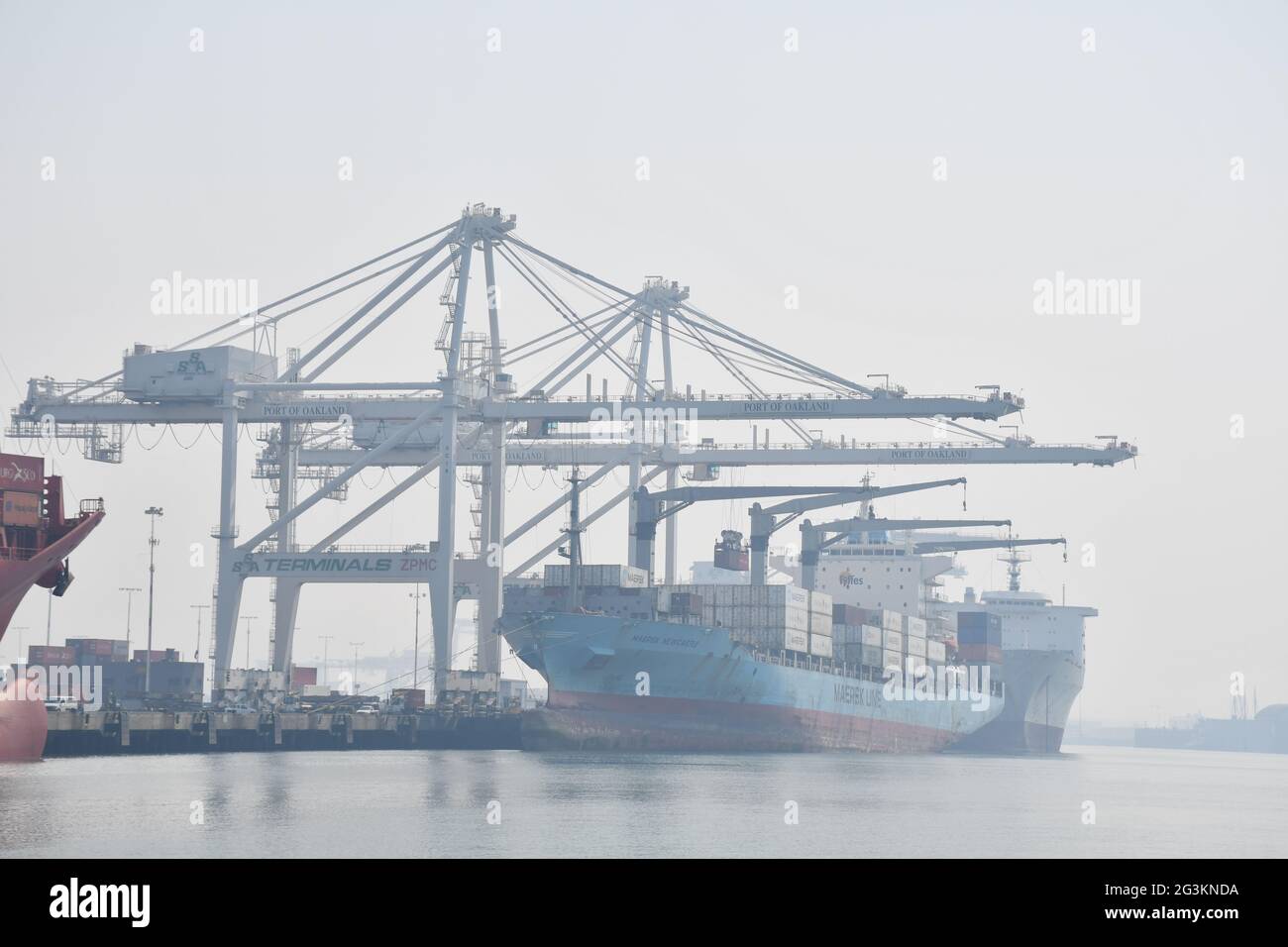 Navi portacontainer caricate a Port of Oakland, California. Il cielo è oscurato a causa del fumo dagli incendi boschivi. Foto Stock