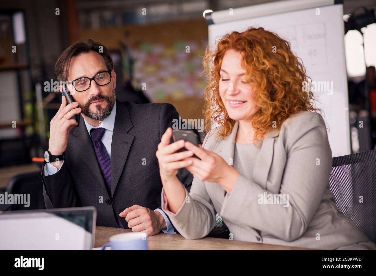 Imprenditore e imprenditrice a lavorare uno spazio di comunicazione sul telefono. Foto Stock