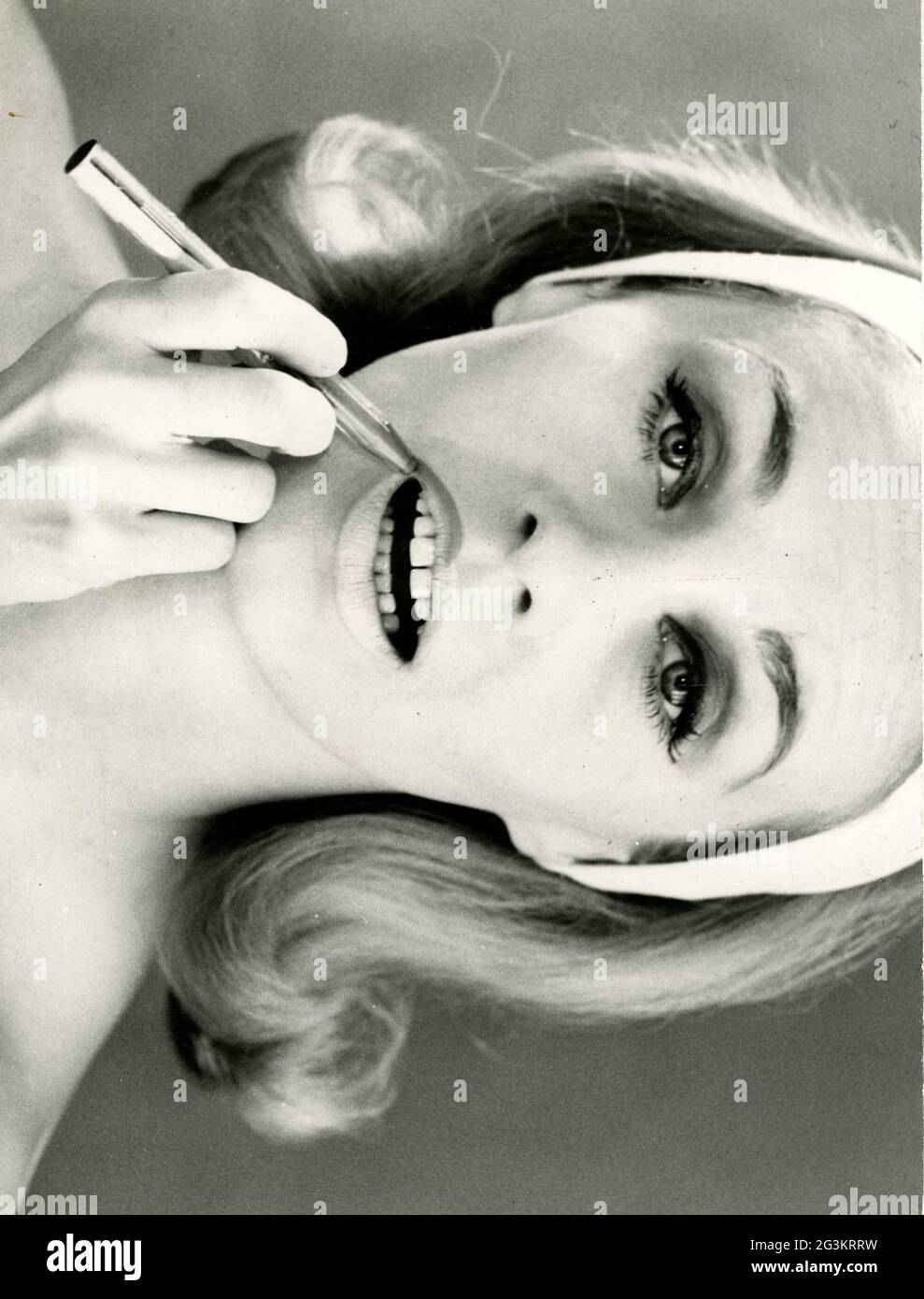 Cosmetici, giovane donna che applica rossetto, anni '60, DIRITTI-AGGIUNTIVI-CLEARANCE-INFO-NON-DISPONIBILE Foto Stock