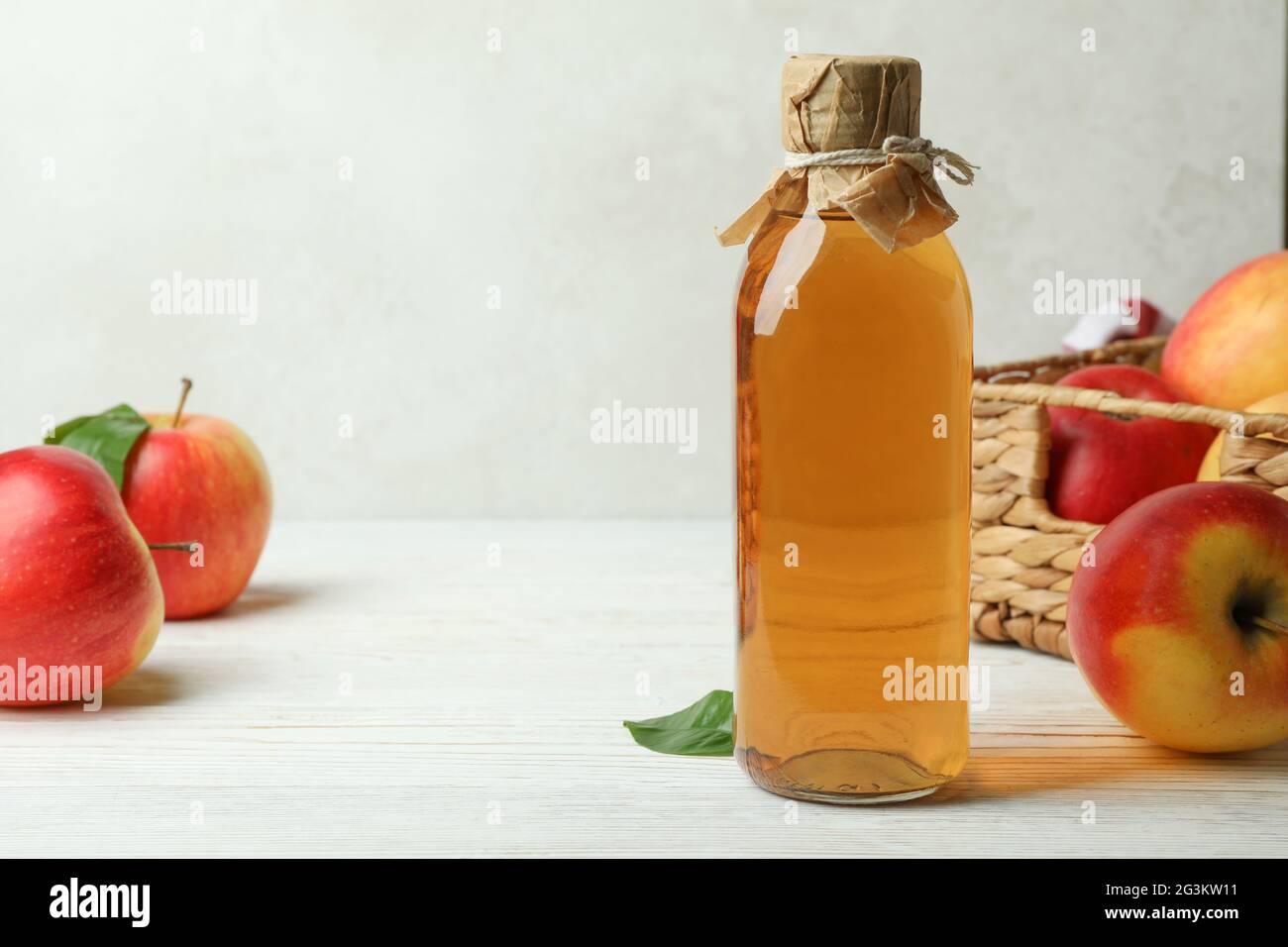 Aceto di mele fatto in casa e ingredienti su tavola di legno bianco Foto Stock