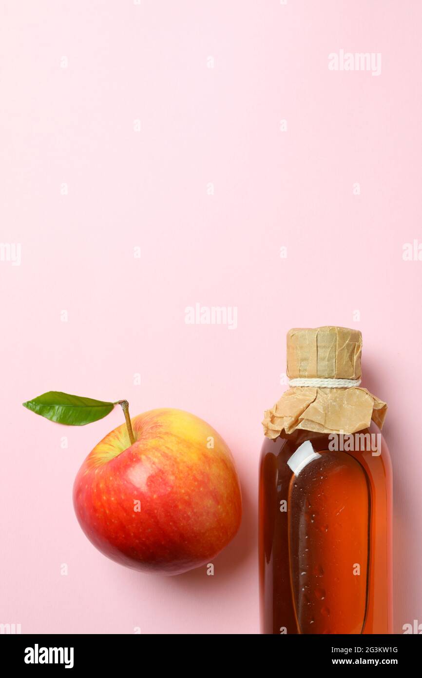 Aceto di mele fatto in casa e ingrediente su sfondo rosa Foto Stock