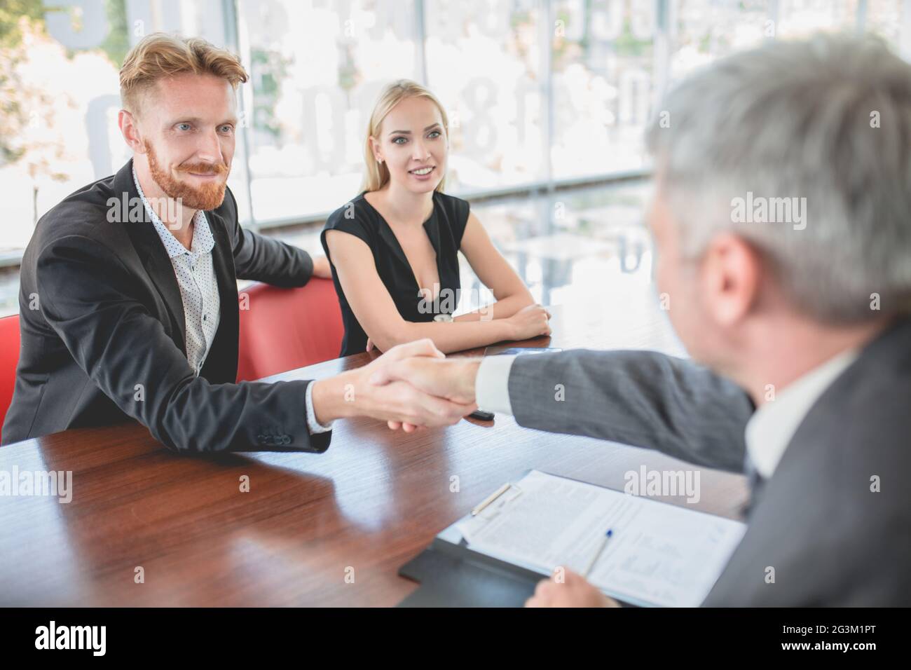 Coppia che piange nuova auto, seduto in ufficio in salone auto. Foto Stock