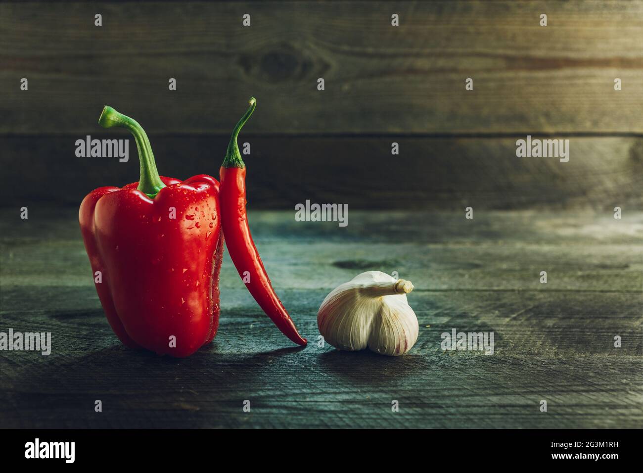 Peperone rosso, peperoncino e aglio su una tavola di legno Foto Stock