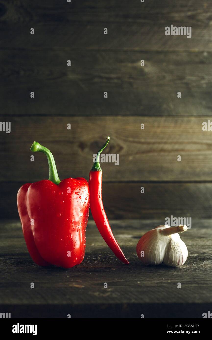 Peperone rosso, peperoncino e aglio su una tavola di legno Foto Stock