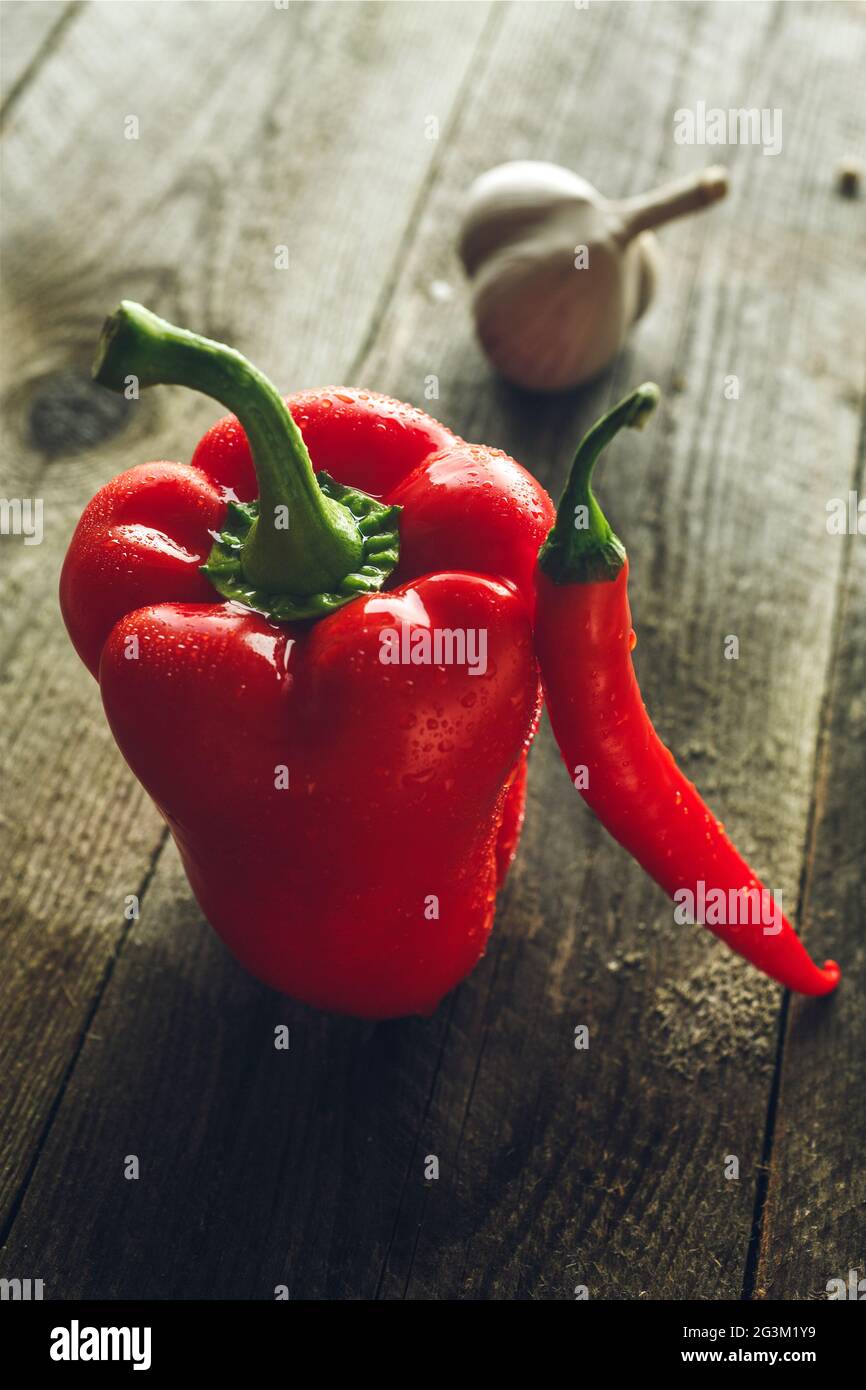 Peperone rosso, peperoncino e aglio su una tavola di legno Foto Stock