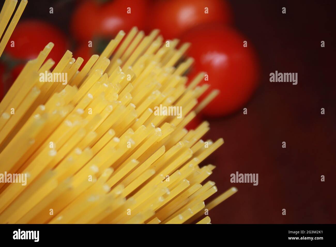 Spaghetti non cotti e stucco di pomodoro su sfondo di legno. Foto Stock