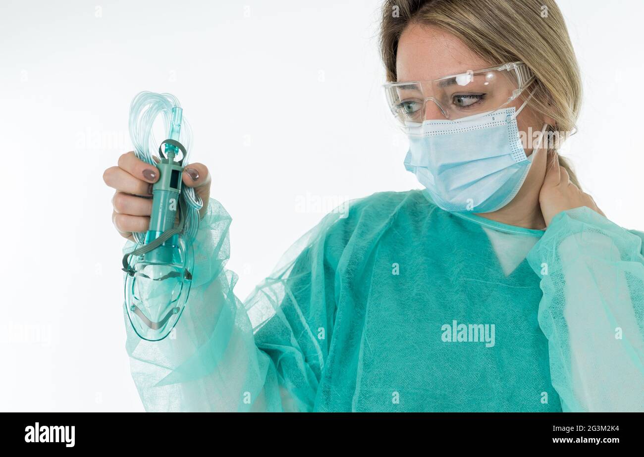 Ritratto di Doctor esausto in maschera protettiva per il viso che tiene il ventilatore non invasivo. Stress emotivo degli operatori sanitari di prima linea, COVID-1 Foto Stock