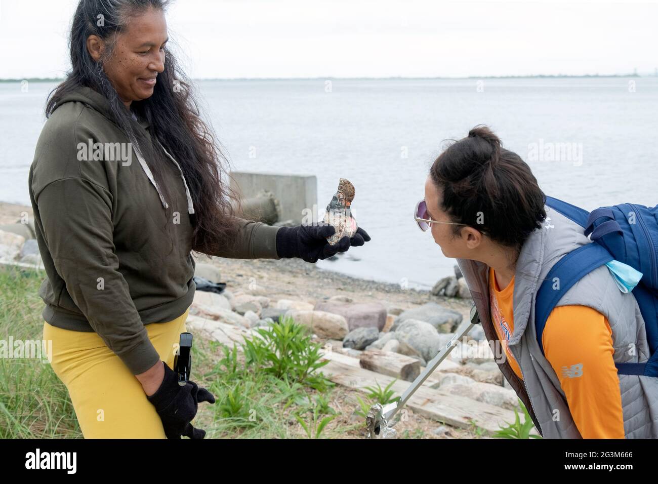 Al progetto 2021 Primhvi Beach Cleanup atJamaica Bay in Queens, 2 donne volontari ispezionano una statua religiosa scartata. Foto Stock