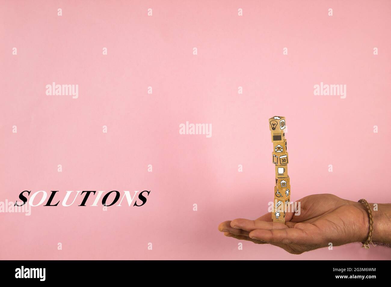 mano che tiene una pila di blocchi di legno in equilibrio con forme e concetto di soluzioni su uno sfondo rosa Foto Stock